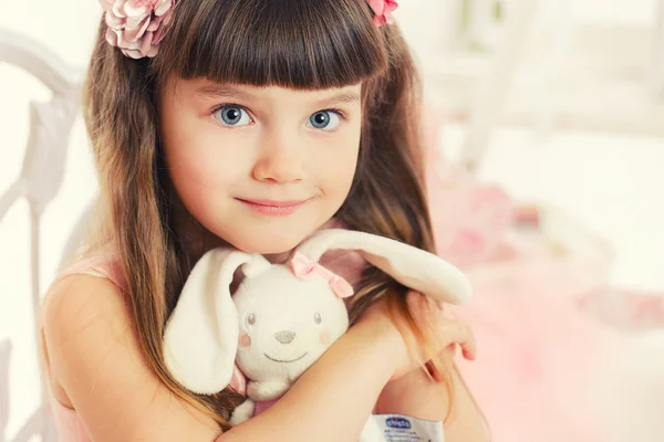 Маленькая девочка с мягкой игрушкой, сидя на стуле — стоковое фото