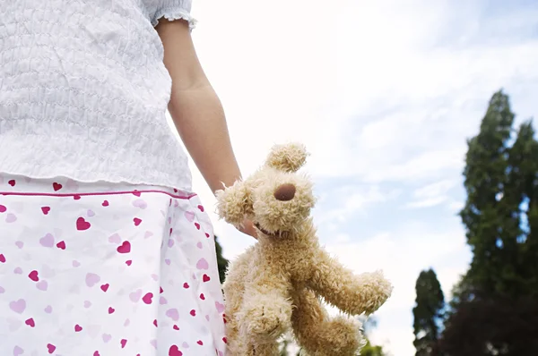 Заделывают детали мягкой игрушки, удерживаемые молодая девушка в парке, против голубого неба — стоковое фото