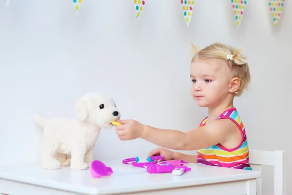 Маленькая девочка, играющая доктора с игрушечным щенком — стоковое фото