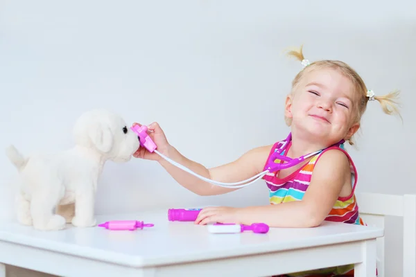 Маленькая девочка, играющая доктора с игрушечным щенком — стоковое фото